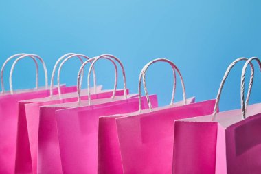 few pink paper shopping bags on blue background  clipart