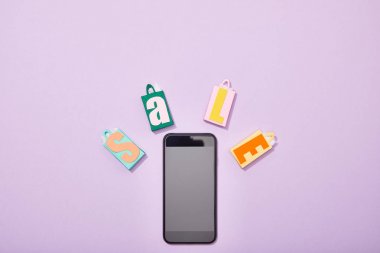 menekşe üzerinde satış yazı ile renkli oyuncak alışveriş torbaları yakın akıllı telefon üst görünümü 