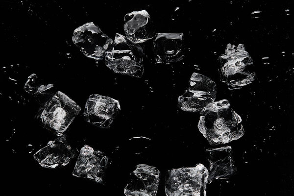 вид сверху на таяние прозрачных освежающих кубиков льда, изолированных на черном

