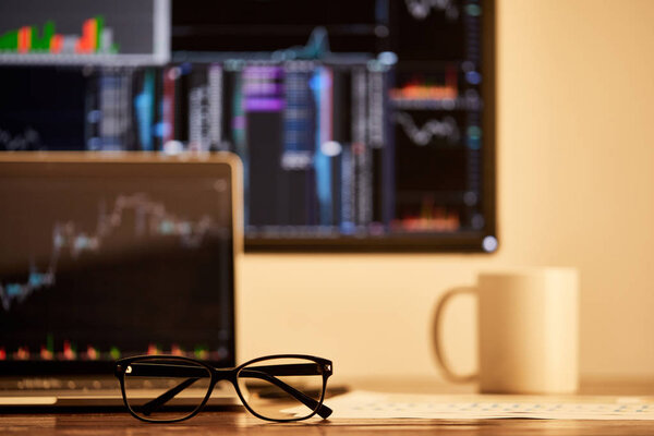 selective focus of glasses on table with digital devices and cup on background 