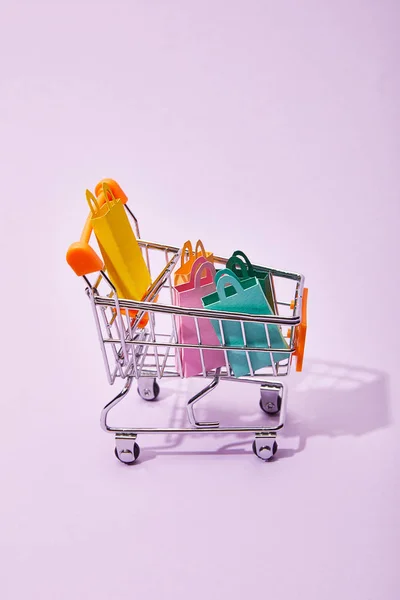 装饰车与彩色纸购物袋在紫罗兰背景 — 图库照片