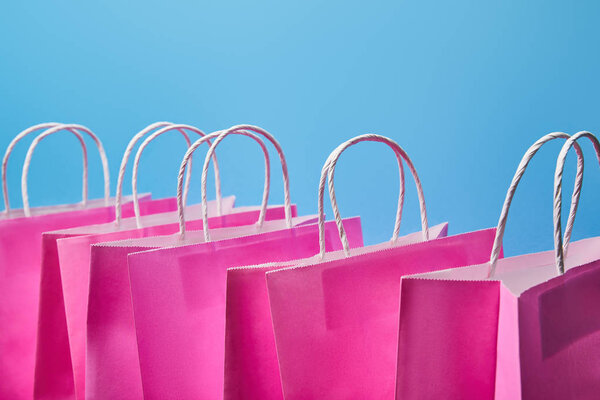 few pink paper shopping bags on blue background 