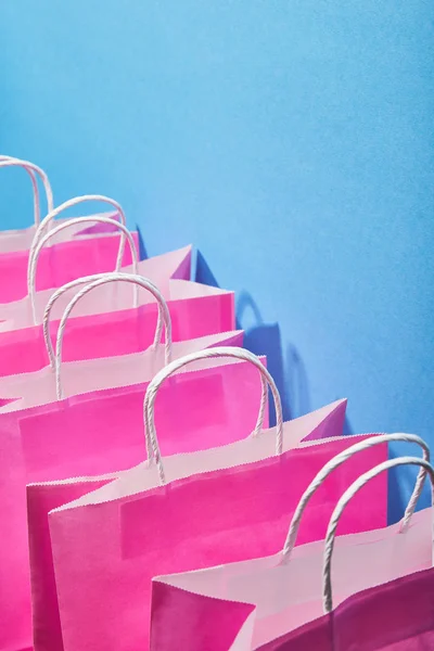 pink shopping bags with white handles on blue background