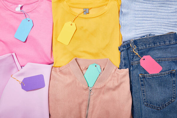 flat lay with paper sale tags on different colorful clothes 