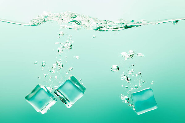 transparent pure water with bubbles and ice cubes on green background