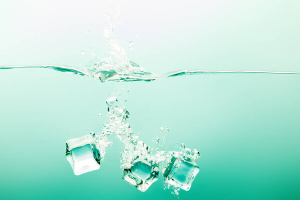 прозрачная чистая вода с брызгами, кубиками льда и пузырьками на зеленом фоне
