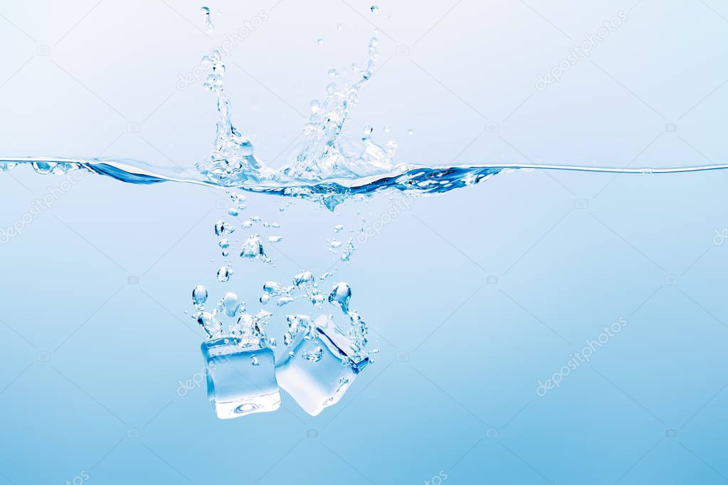 transparent water with splash, bubbles and ice cubes on blue background