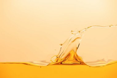 sarı üzerinde izole sıçrama ve dalga ile sarı parlak sıvı
