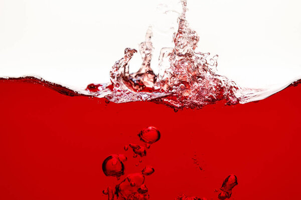 red bright liquid with splash and underwater bubbles isolated on white