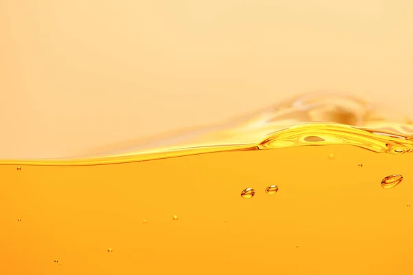 黄色に分離されたスプラッシュと気泡を持つ波状の黄色の明るい液体 — ストック写真