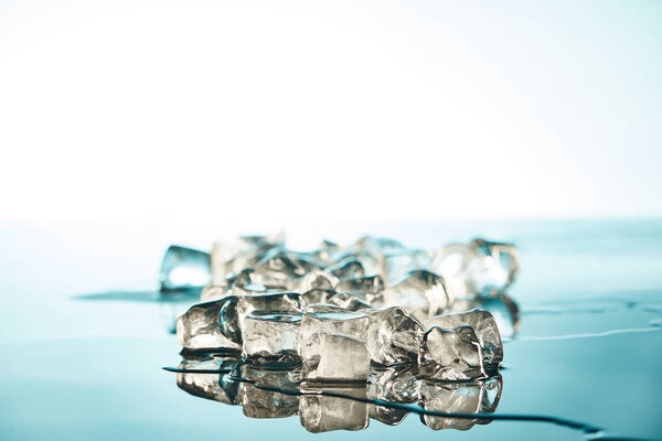 stack of transparent melting ice cubes on emerald and white background