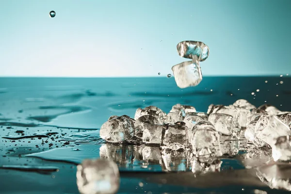 エメラルドと白の背景に水たまりを持つ透明な溶融氷キューブ — ストック写真