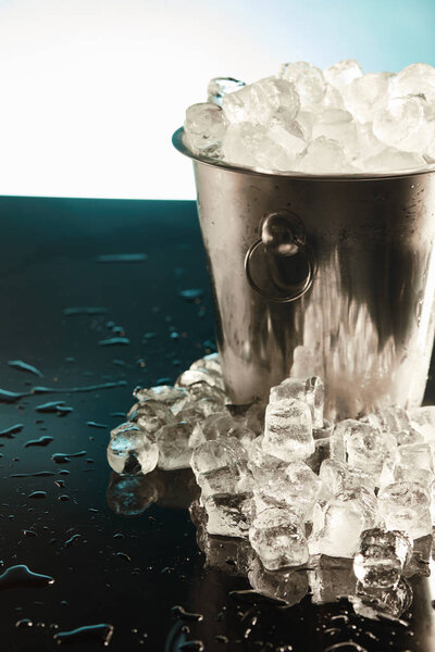 transparent ice cubes in metal bucket on emerald surface