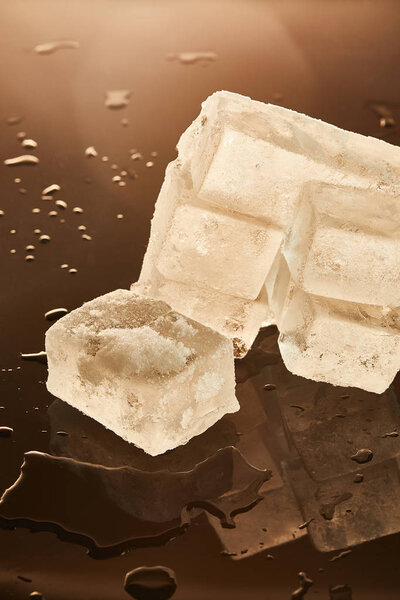 stack of ice cubes with puddles on brown background