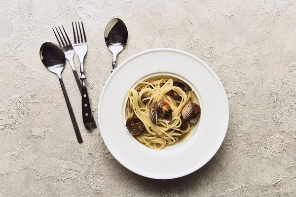 美味的意大利面与软体动物附近的餐具纹理白色背景的顶视图 — 图库照片