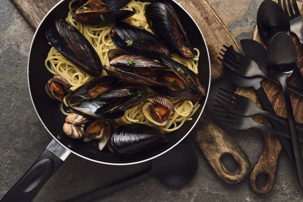 在风化灰色背景的煎锅中 可口的意大利面与软体动物和贝类的顶视图 — 图库照片
