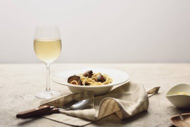 Italian pasta with seafood served with white wine, napkin and cutlery isolated on grey clipart