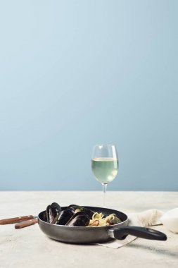 delicious Italian pasta with seafood served in frying pan with white wine isolated on blue clipart