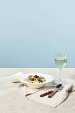 delicious Italian spaghetti with seafood served with white wine on napkin near cutlery isolated on blue clipart