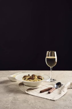 deniz ürünleri ile lezzetli İtalyan spagetti beyaz şarap ve siyah izole çatal yakın peçete üzerinde rendelenmiş peynir ile servis