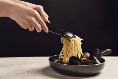siyah izole tavadan deniz ürünleri ile lezzetli İtalyan spagetti alarak kadın kırpılmış görünümü
