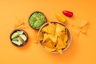 turuncu arka plan üzerinde gevrek Meksika nachos, guacamole, kireç ve biber üst görünümü