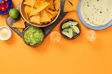 Meksika nachos guacamole, peynir sosu, biber, ıhla, Tekila ve tortilla kopya alanı ile turuncu arka plan ile ahşap kesme tahtası üzerinde servis