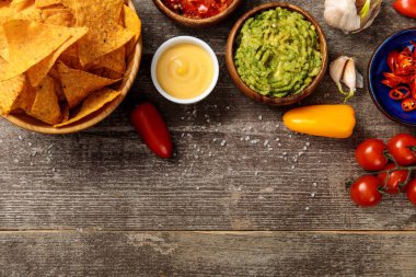 Meksika nachos üst görünümü tuz ile ahşap masada guacamole, peynir sosu ve salsa ile servis