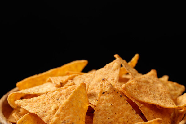 crispy tasty Mexican nachos in wooden bowl isolated on black