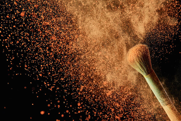 красочный взрыв оранжевого порошка на черном фоне
