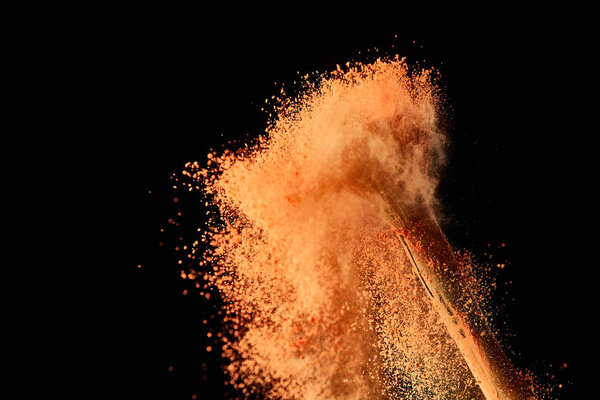 cosmetic brush with colorful paint explosion on black background