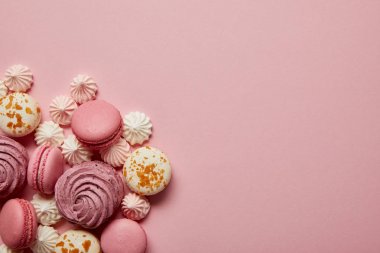 Delicious sweet pink and white macaroons with meringues on pink background clipart