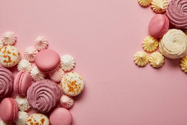 Pembe arka planda lezzetli tatlı makaronlar ve renkli bezeler