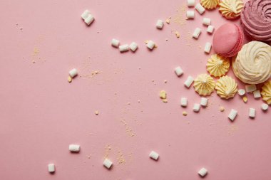 Pembe arka plan üzerinde sarı parçalar ile tatlı pembe macaroons, bezeler ve marshmallowüst görünümü