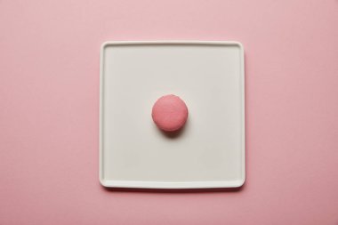Pembe arka plan üzerinde büyük kare beyaz çanak pembe macaroon üst görünümü