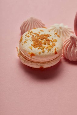 Pembe arka plan üzerinde sarı parçalar ve bezeler ile beyaz makaron