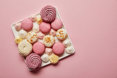 Pembe arka plan üzerinde kare çanak çeşitli Fransız macaroons ve bezeler üst görünümü