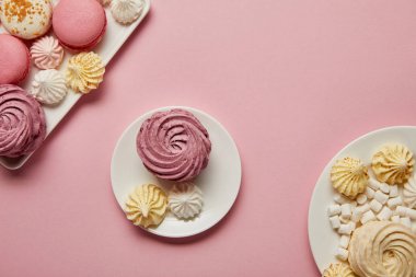 Pembe arka plan tabaklarda macaroons ve marshmallows ile tabak üzerinde küçük bezeler ile yumuşak pembe zephyr 