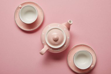 Pastel pembe noktalı çaydanlık ve pembe arka plan üzerinde tabaklar ile bardak