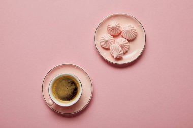 Noktalı tabak ve pembe arka plan üzerinde kahve fincan üzerinde küçük pembe bezeler üst görünümü