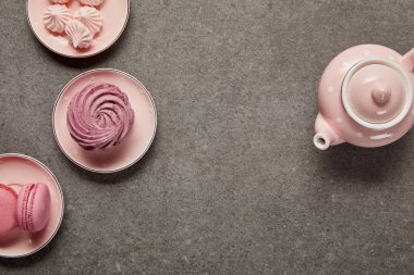 Gri arka planda bezeler ve zephyr ile noktalı çaydanlık ve tabaklar ile pembe üst görünümü