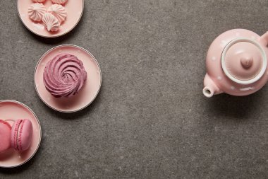 Gri arka planda bezeler ve pembe zephyr ile pembe çaydanlık ve tabaküst görünümü