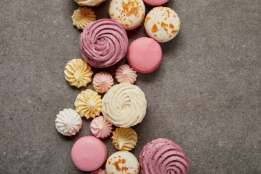 Gri arka plan üzerinde tatlı yumuşak zephyr, küçük taze bezeler ve Fransız macaroons üst görünümü