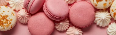 Pembe arka planda küçük pembe ve beyaz bezeler ile lezzetli çeşitli macaroons