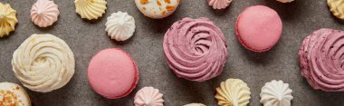 Tasty assorted small meringues, fresh soft zephyr and sweet pink macaroons on gray background clipart