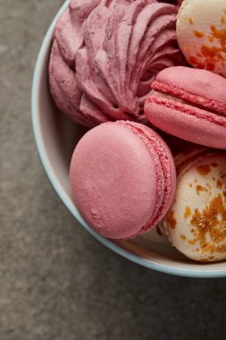 Gri arka plan üzerinde beyaz ve mavi kase yumuşak pembe zephyr ile Gurme tatlı pembe macaroons