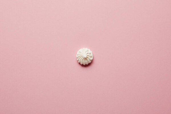 Top view of small white meringue in center on pink background