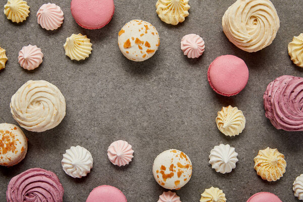 Top view of pink and white macaroons with meringues on gray background