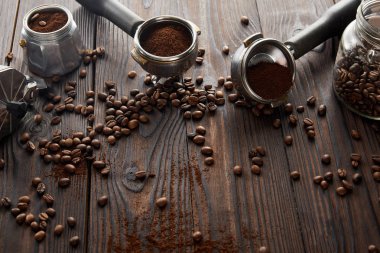 Kahve çekirdekleri ile koyu ahşap yüzeyüzerinde portafilters ve cam kavanoz yakınında Gayzer kahve makinesi