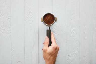 Beyaz ahşap yüzey üzerinde kahve ile portafilter tutan adam üst görünümü